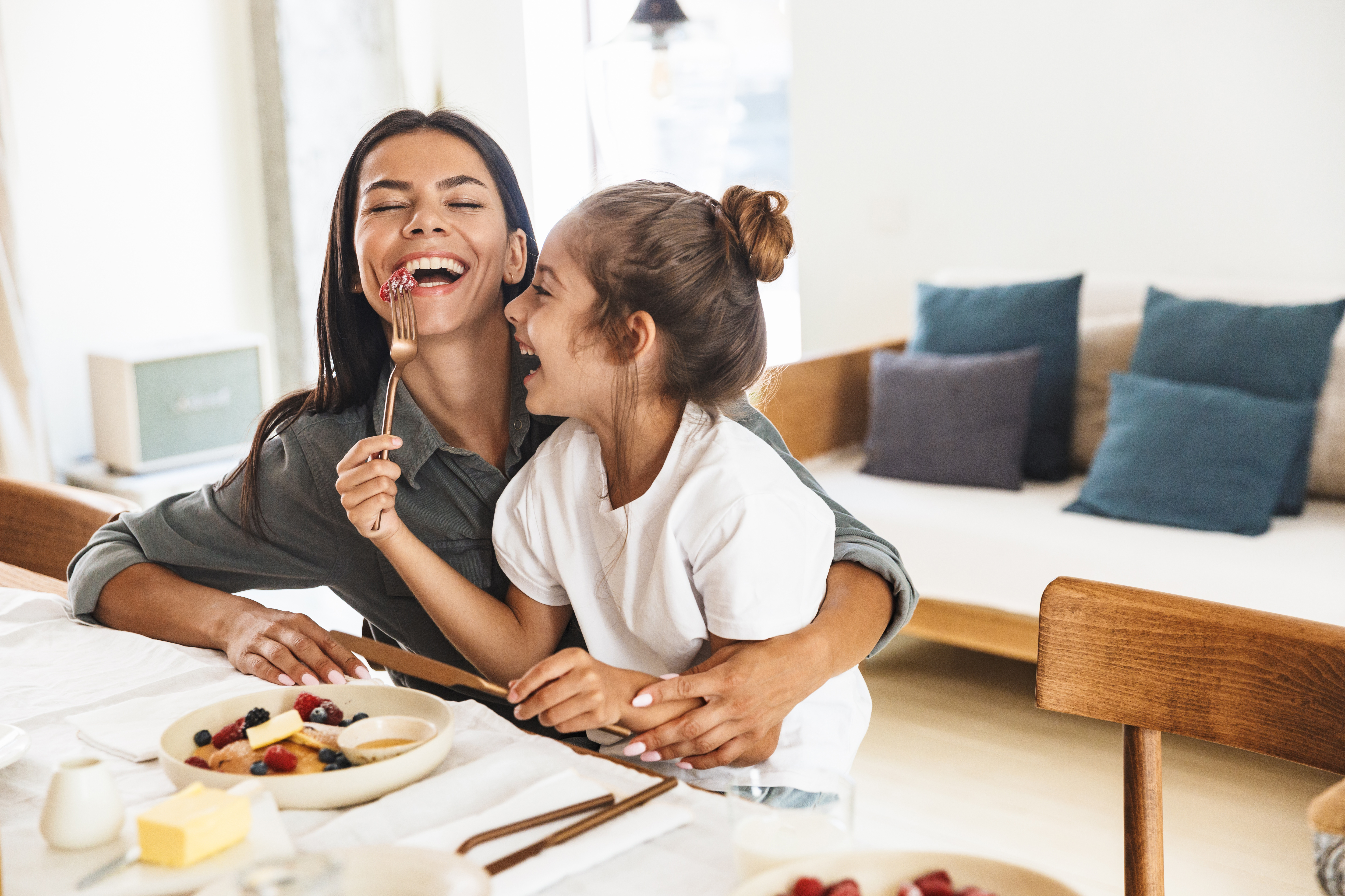 A woman and child smiling together over a meal at home.