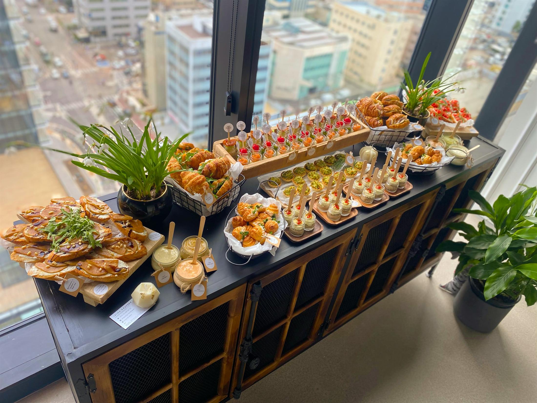 Chef-prepared catering spread arranged beside office windows.